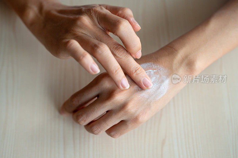 女士在干燥的手上涂抹保湿霜
