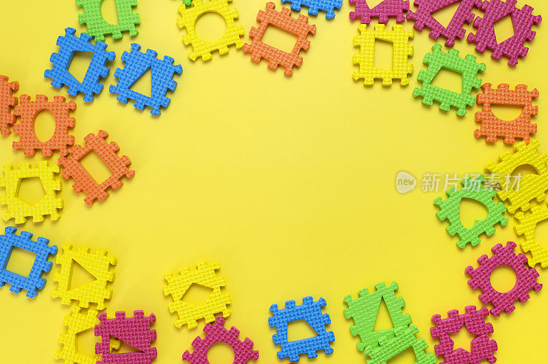 框架从软儿童的彩色拼图与各种数字在黄色背景平lay。幼儿创造力游戏，发展思维，教育。抽象的背景