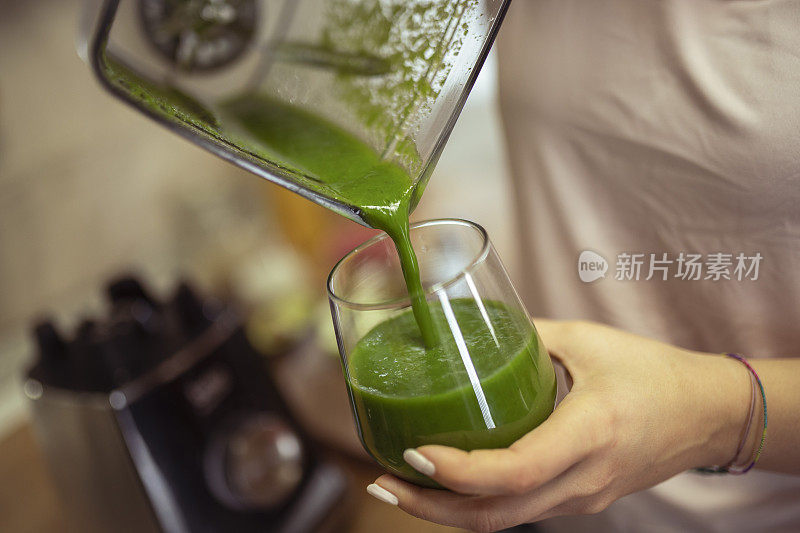 一个女人的手往酒杯里倒冰沙的特写