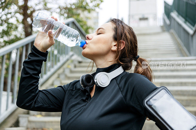 年轻的运动妇女从水瓶喝水