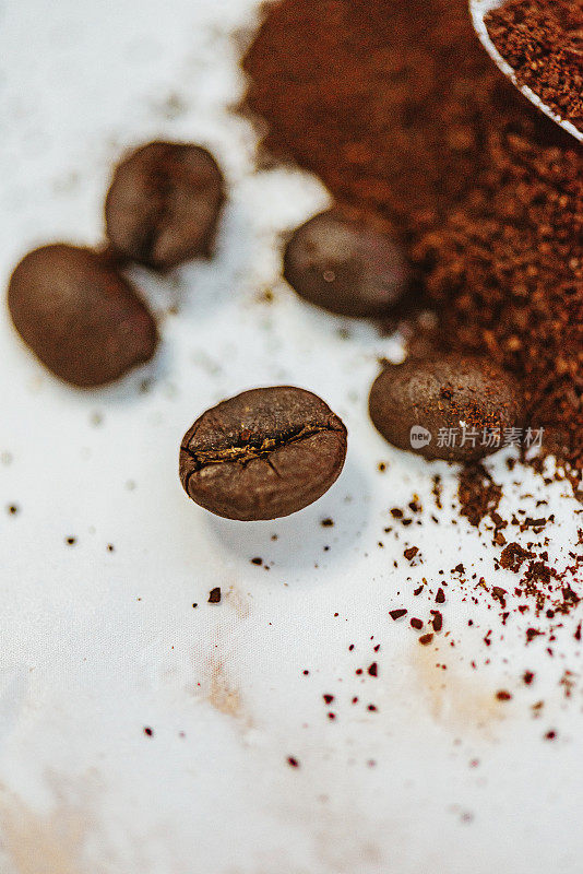 研磨的咖啡豆和整颗咖啡豆放在白色大理石上