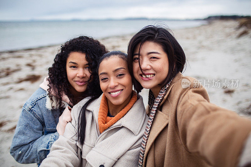 三个年轻女子在海滩上自拍