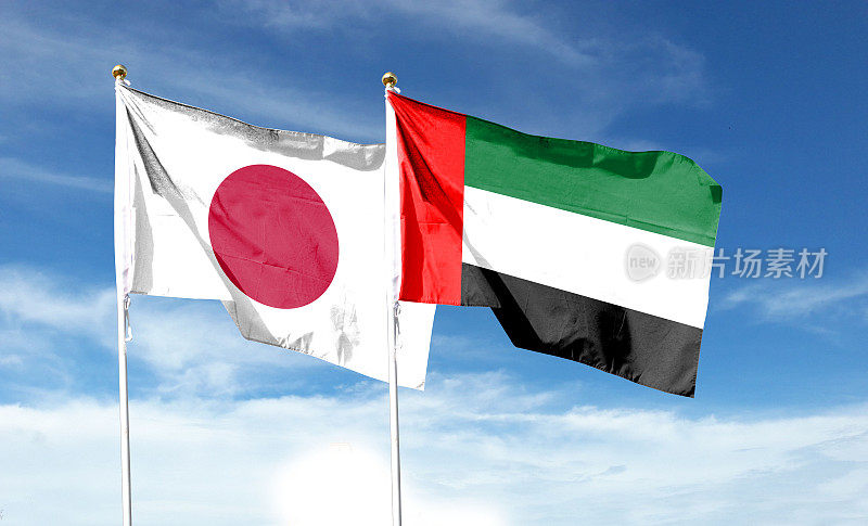 多云天空上的日本国旗和阿联酋国旗。在天空中摇曳