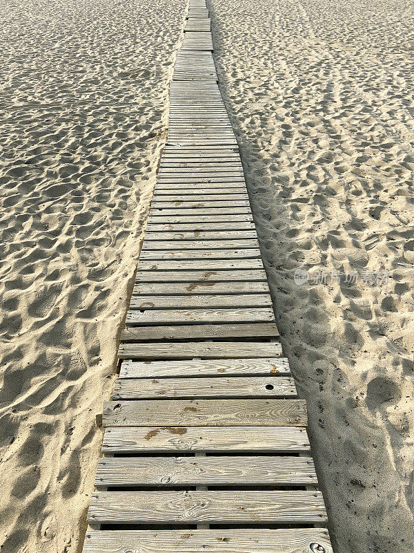 海滩上的沙滩上有脚印的木头小径