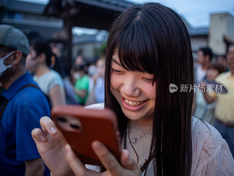 年轻女子在人群中用智能手机打字