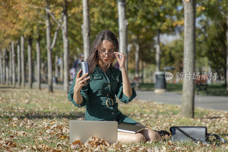 一个年轻的黑发女人在公园里摆弄她的电脑