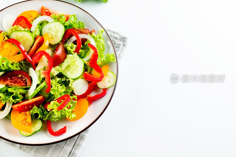 蔬菜沙拉，新鲜的西红柿，黄瓜，洋葱，生菜在白色盘子。