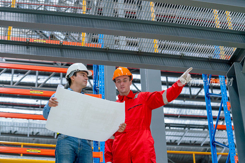 近景和低景工程师手持图纸，技术工人在工厂工作场所靠近电气或空轨列车的轨道。