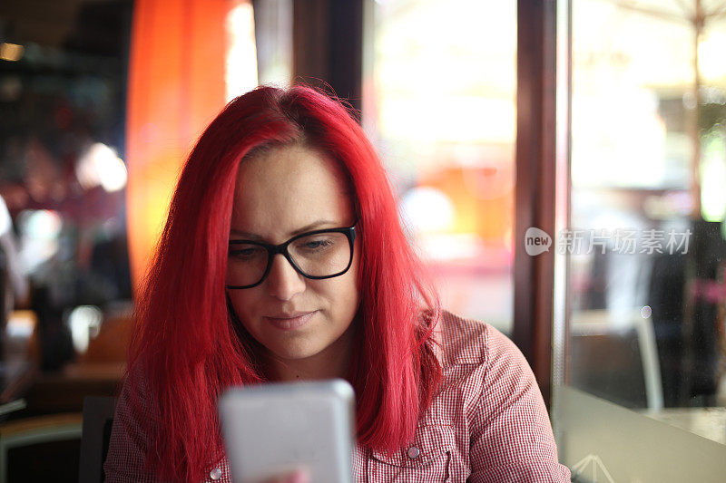 一个女人在咖啡馆用手机发短信