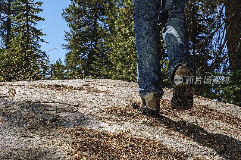 徒步旅行者穿着登山靴穿过岩石和松针