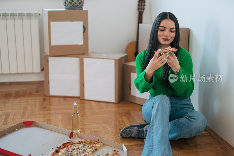 一位年轻女子正坐在地板上吃披萨