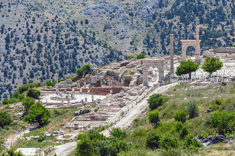 古城遗址、石柱、拱门、小路，掩映在群山之中。鸟瞰图。萨加拉索斯，阿格拉森，土耳其(土耳其语)