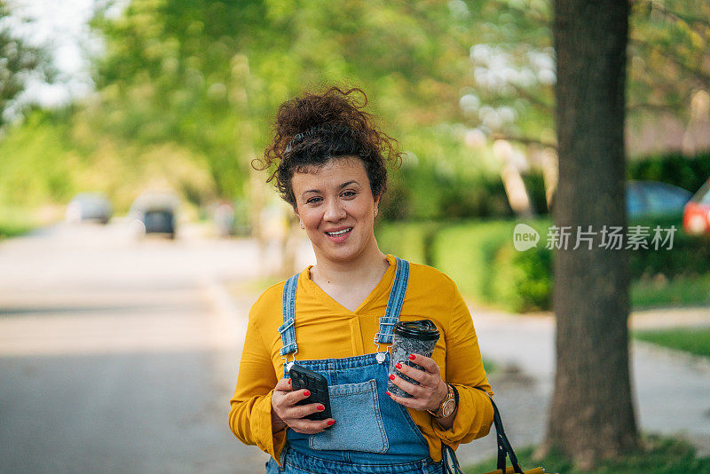 一个轻松的卷发女人一边走一边打电话。