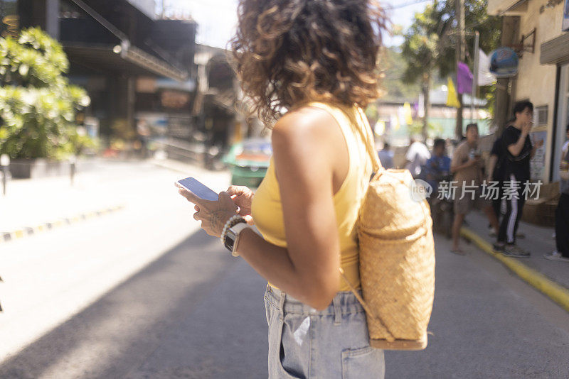 一名无法辨认的女子在城市街道上行走时使用一款手机应用程序来使用GPS