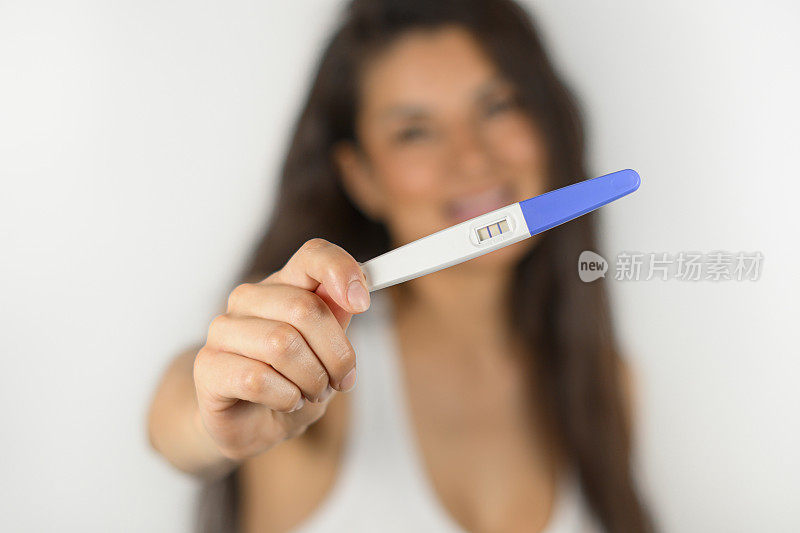 幸福的女人拿着的怀孕测试结果是阳性的。母亲的概念
