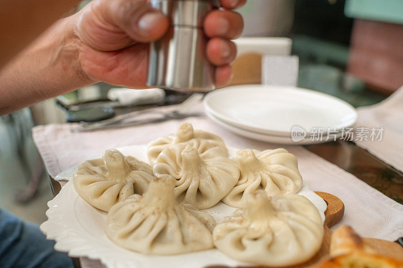 格鲁吉亚传统美食。一名男子正在吃Khinkali——美味的饺子，里面有肉、香草和香料。