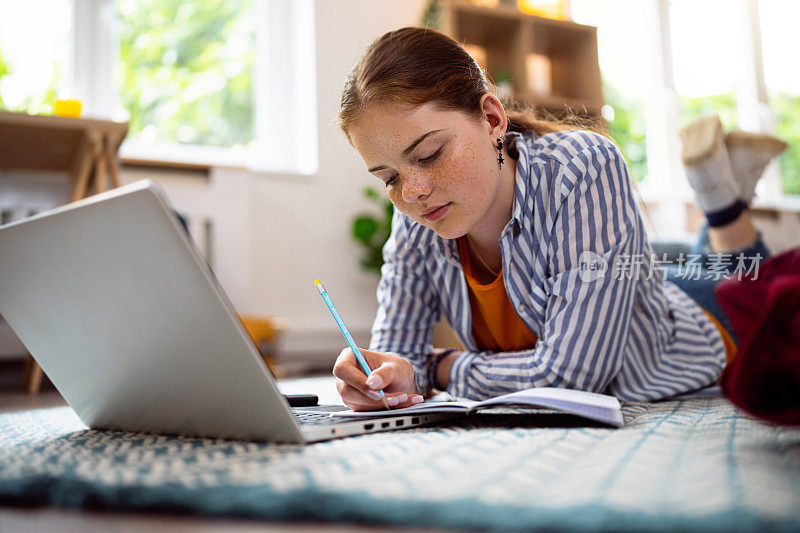 红发少女边用笔记本电脑边做作业