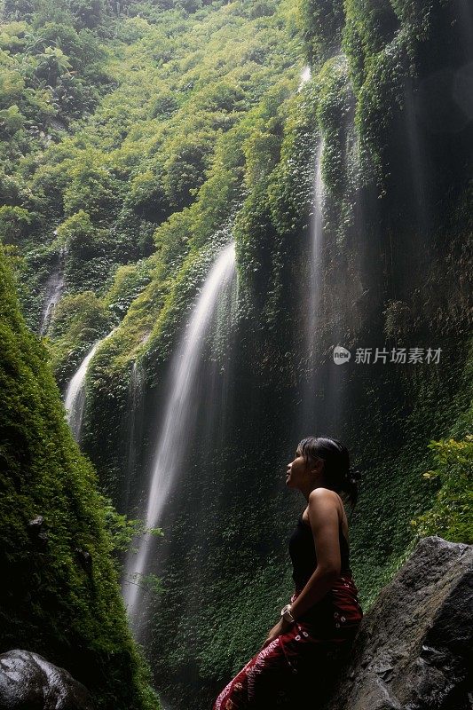 穿着红色蜡染布的东南亚女孩在马达卡里普拉瀑布下