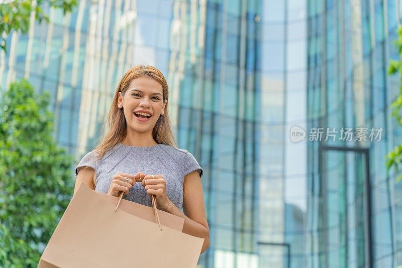 优雅的女商人在金融区拎着购物袋