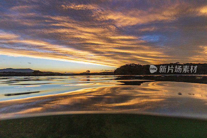 明亮戏剧性的金色天空在日落反射在水面上