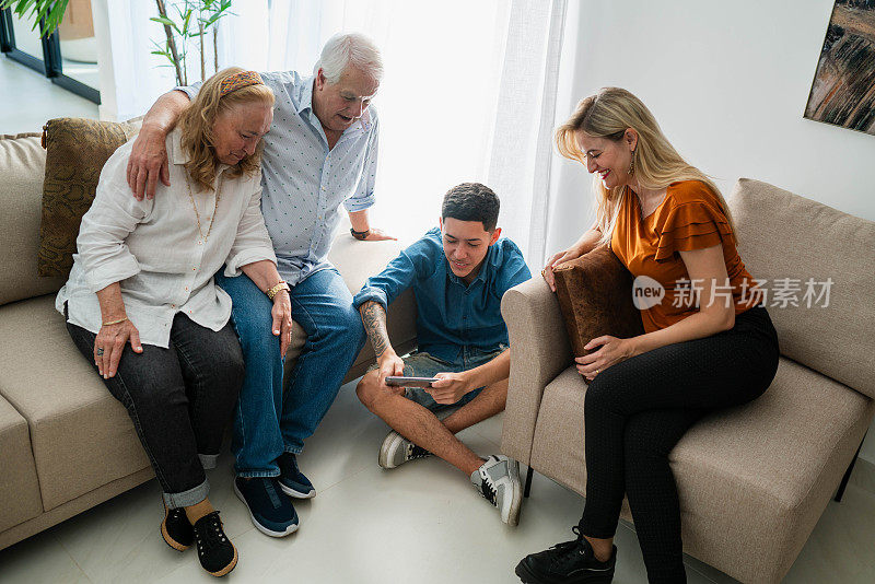 几代同堂的一家人坐在家里，用手机看热气腾腾的东西