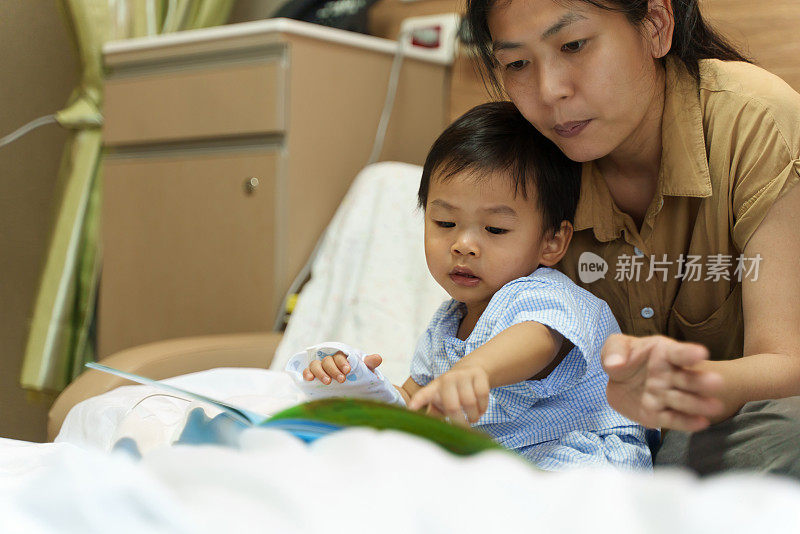 可爱的亚洲孩子感染了病毒，他照顾好自己，和妈妈一起看书，在医院接受抗生素药物和输液盐水，等待康复。婴儿保健医疗理念。