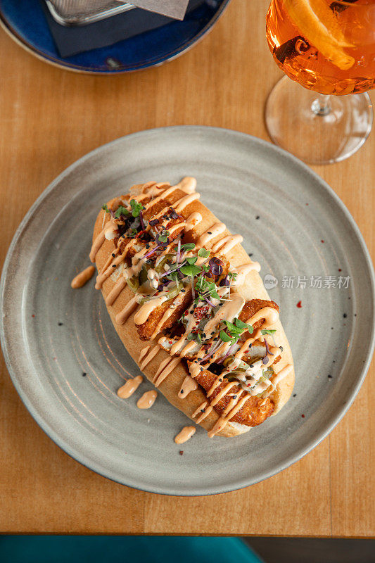 炸鸡三明治包与墨西哥辣椒酱在餐厅的桌子上，饮料和薯条