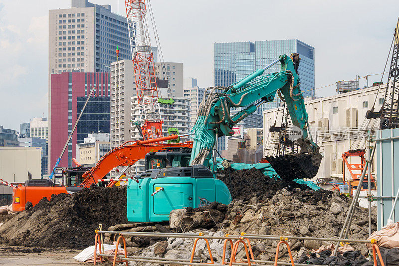 在城市建筑工地进行施工的重型机械，如挖掘机和起重机