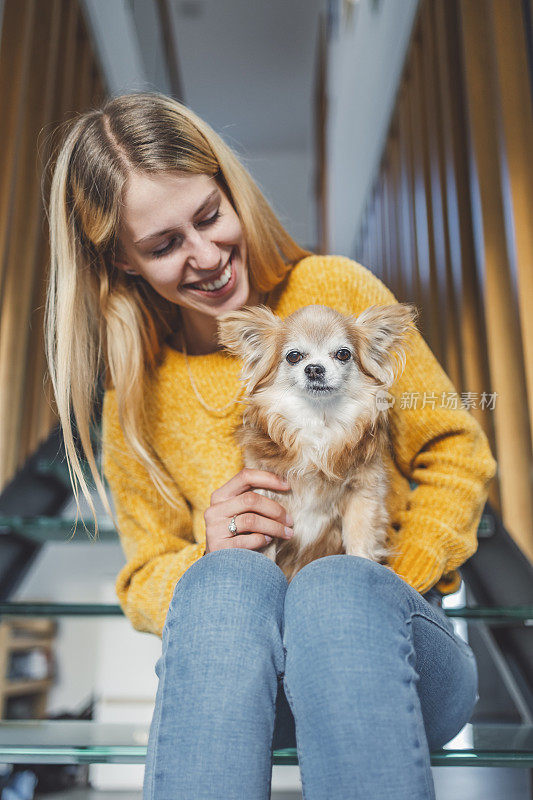 一个女人带着一只吉娃娃狗在客厅里