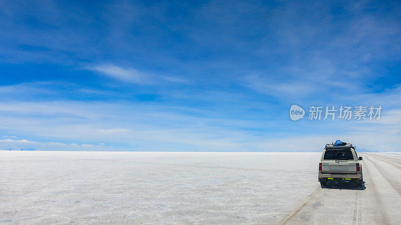 旅游吉普车驶过乌尤尼盐湖(后视图)