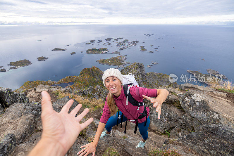 徒步旅行者帮助队友到达山顶