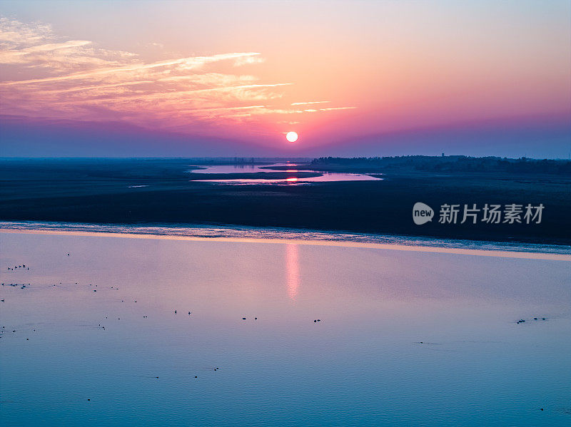 日落在海上，帐篷在日落的海滩上