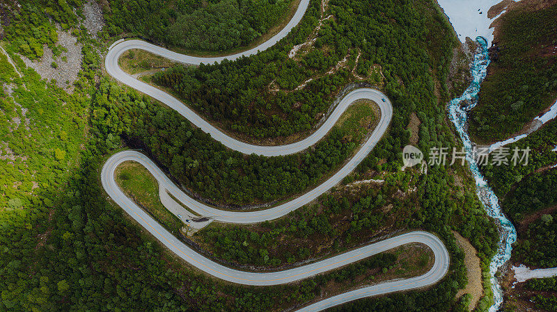 蓝色汽车在挪威风景秀丽的绿山谷的发夹路的鸟瞰图