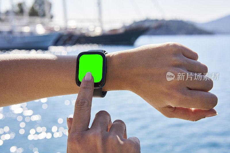 手戴智能手表在模糊的海洋背景。可穿戴设备概念