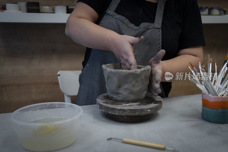 女陶工在陶轮上用湿粘土制成的围裙状花瓶里