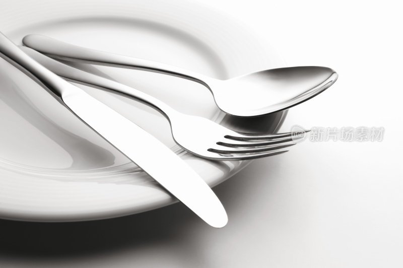 特写的银刀，勺子和叉子设置在一个盘子上