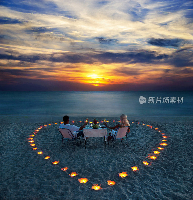 一对年轻夫妇在海滩上共享浪漫晚餐