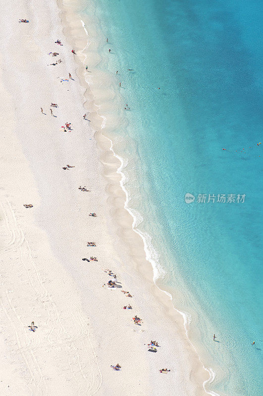 亮蓝色的地中海海滩，上面有日光浴者