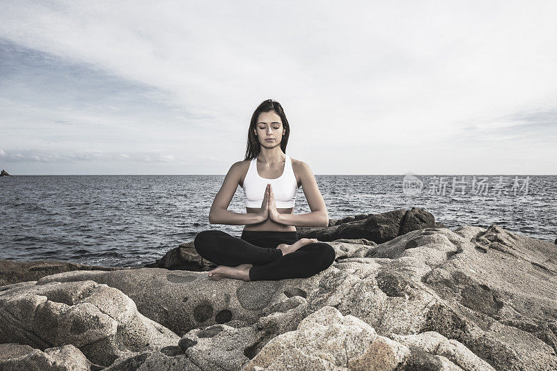 女人在瑜伽莲花pose在海上