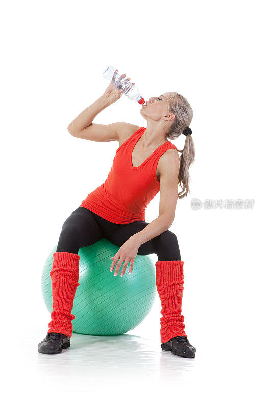 经过艰苦的训练:女子坐在球上，喝水。