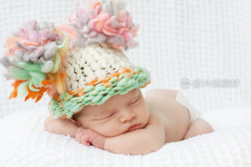 熟睡的新生儿用傻乎乎的绒球帽手工编织