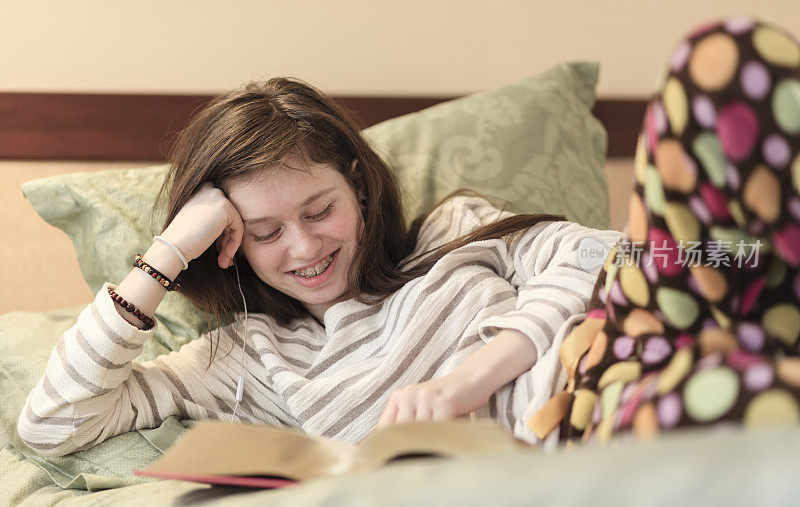 十几岁的女孩穿着睡衣在床上看书