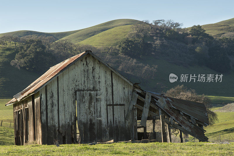 废弃的农场建筑，背景是小山