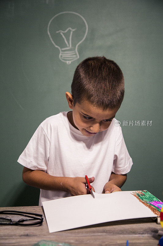 用剪刀剪纸的男孩