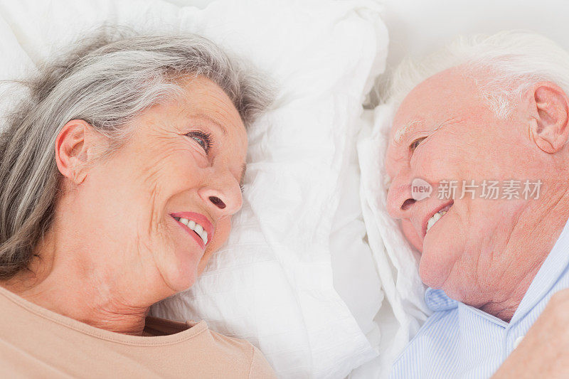 躺在床上的夫妻对着对方微笑