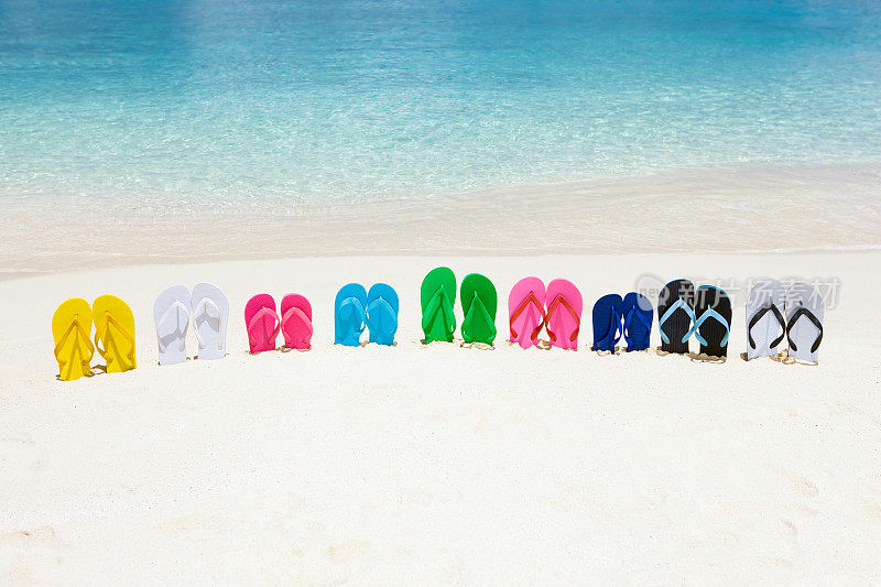 在完美的加勒比海滩上，白色的沙滩上穿着五颜六色的凉鞋