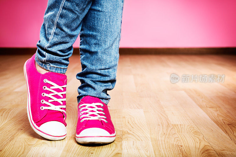 穿着牛仔裤和粉色运动鞋的尴尬、害羞的脚:可爱!