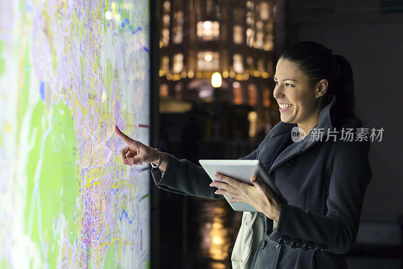 游客在晚上用平板电脑指着地图