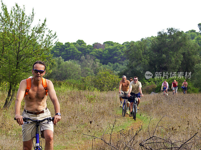 游客骑着自行车在Mljet上穿过田野。