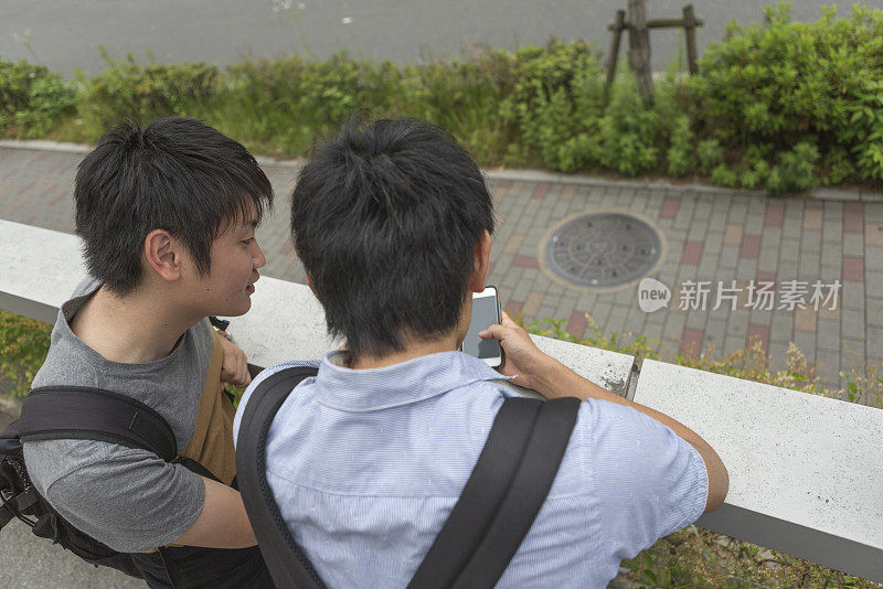 在日本京都的街道上，年轻的日本学生正在查看智能手机